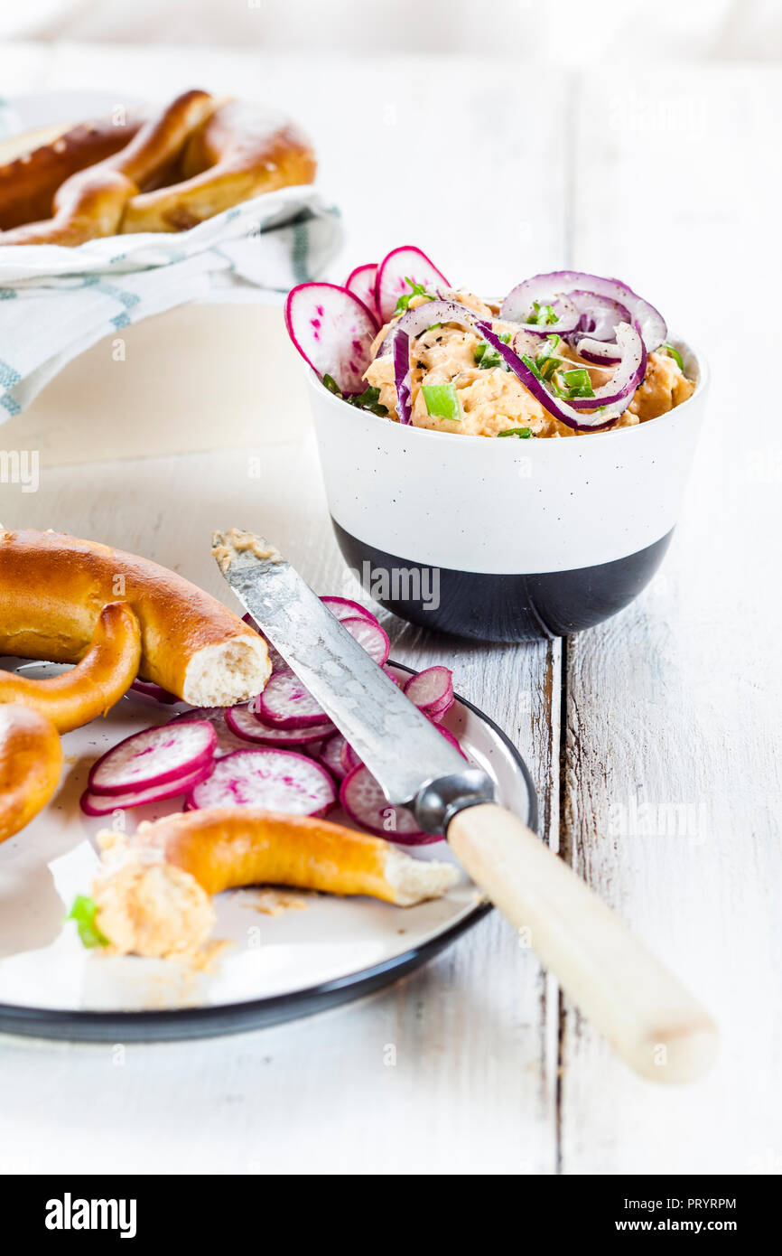 Obatzda avec oignon rouge, radis, oignon de printemps et bretzel Banque D'Images