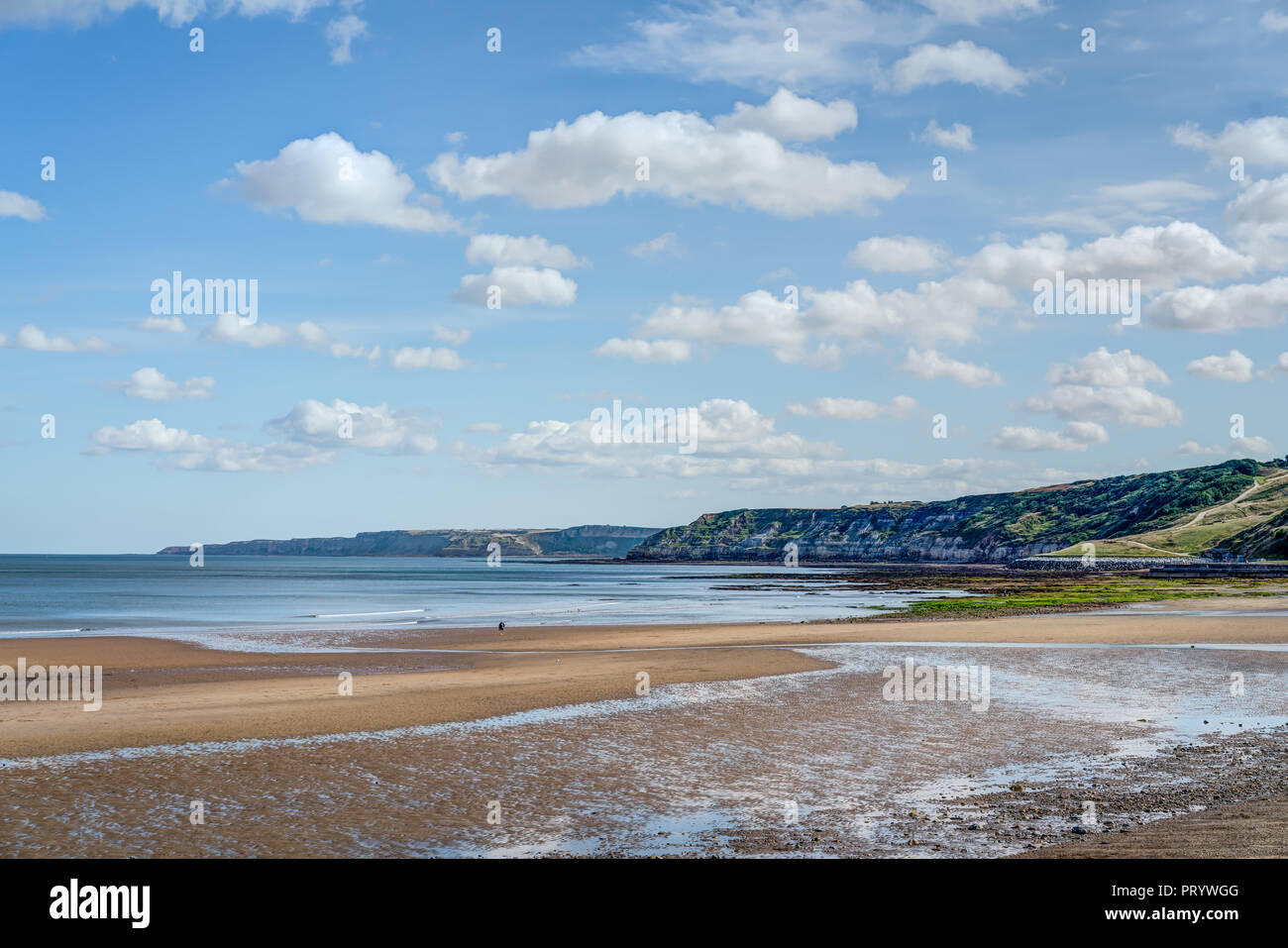 Vers le bas l'extrémité sud de la plage de sable de Scarborough holiday resort en regardant les falaises rocheuses à Filey Brigg dans la distance. Belle journée ensoleillée Banque D'Images