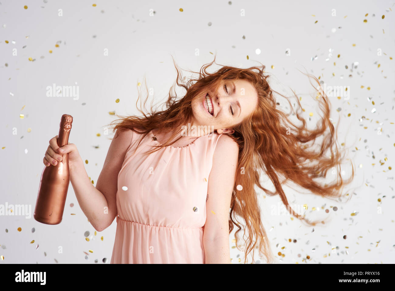 Portrait of happy young woman dancing avec bouteille de champagne Banque D'Images