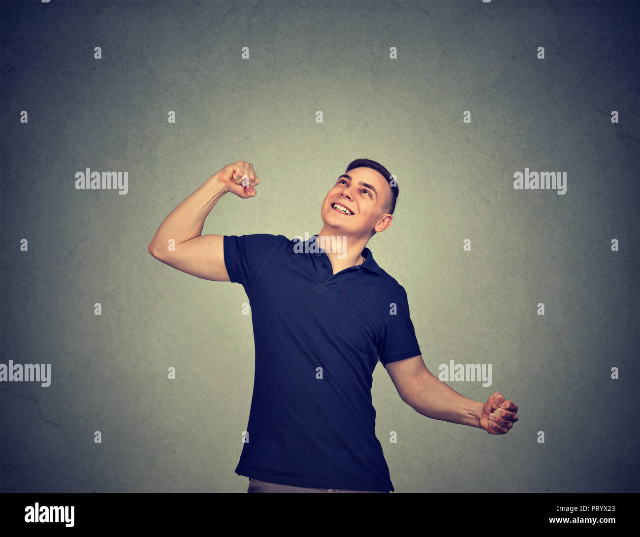 Cheerful young man holding fists gaiement dans l'excitation de la réussite à la haut sur fond gris Banque D'Images