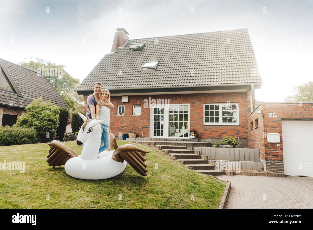 Portrait of smiling mature couple avec piscine gonflable jouet dans jardin de leur maison Banque D'Images
