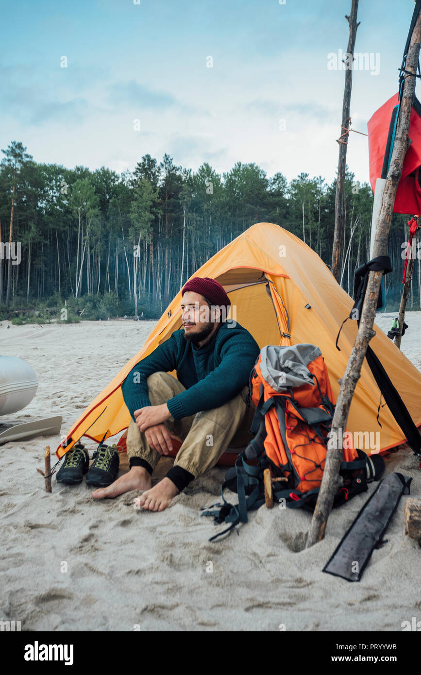 Backpacker assis devant sa tente sur la plage Banque D'Images