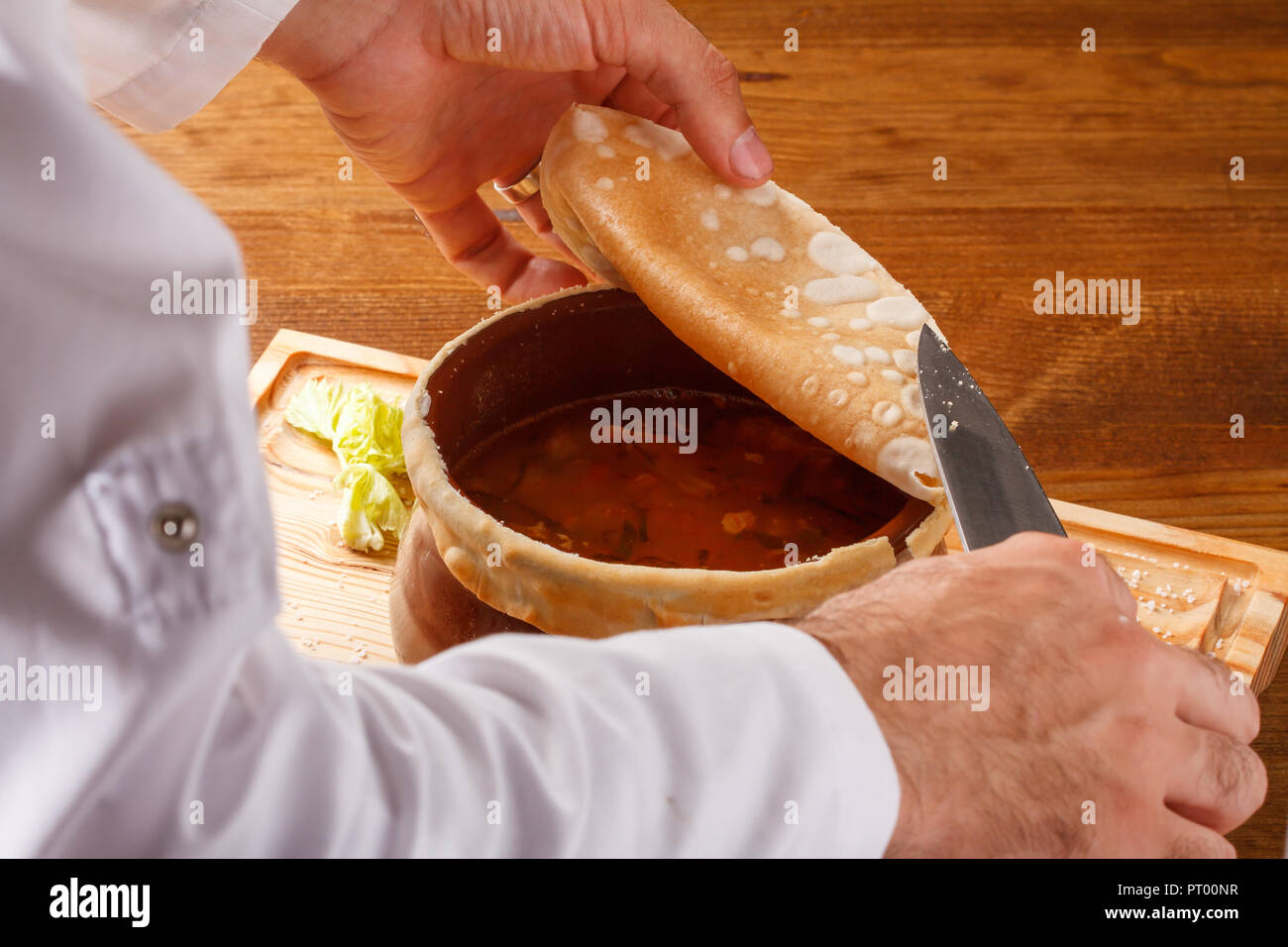 Putuk / Piti - ragoût arménien traditionnel de pois chiches et d'agneau servi dans un pot en argile recouvert d'un pain plat. Banque D'Images