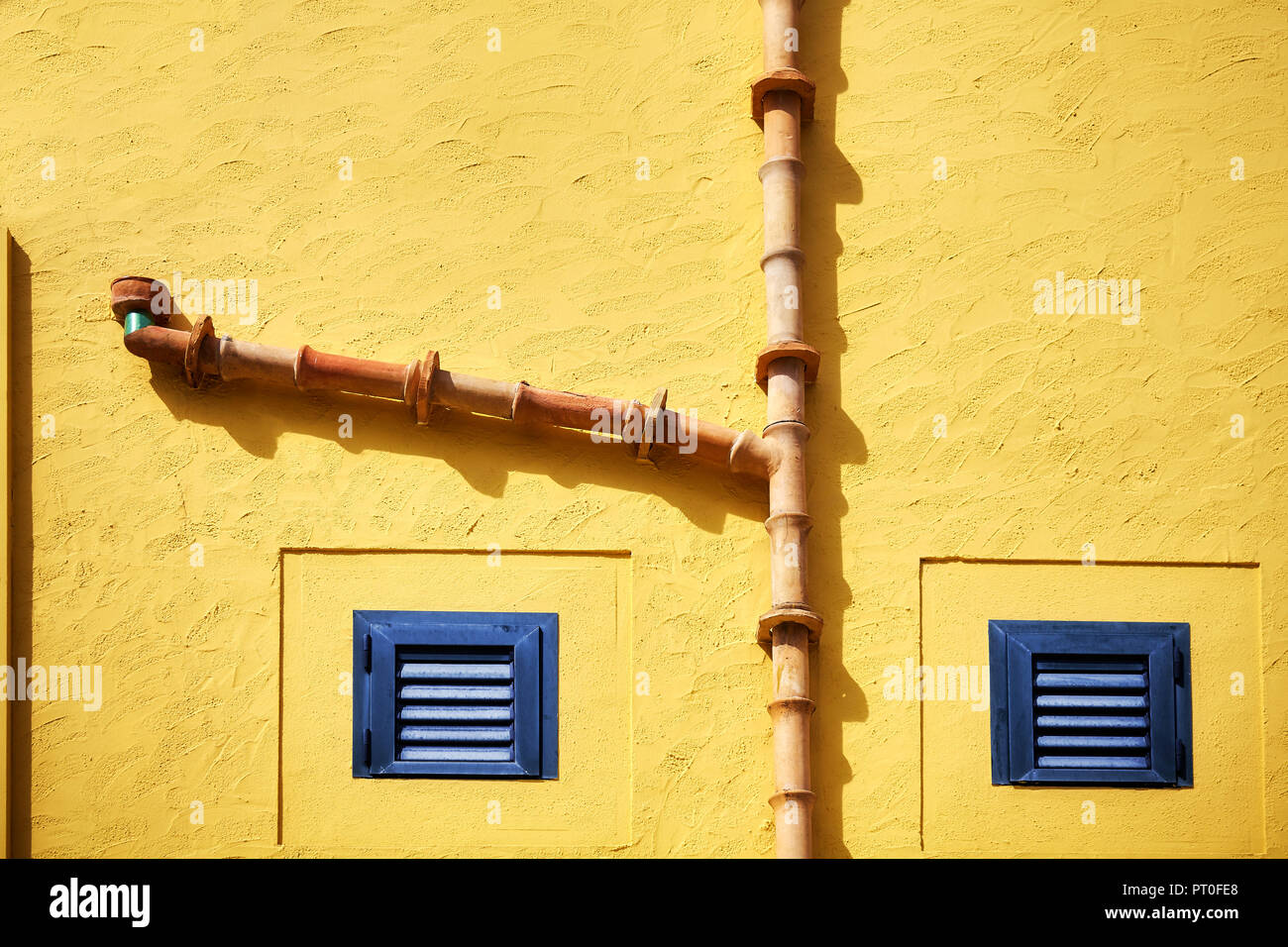 Mur jaune en céramique avec gouttière et deux volets, abstract background. Banque D'Images
