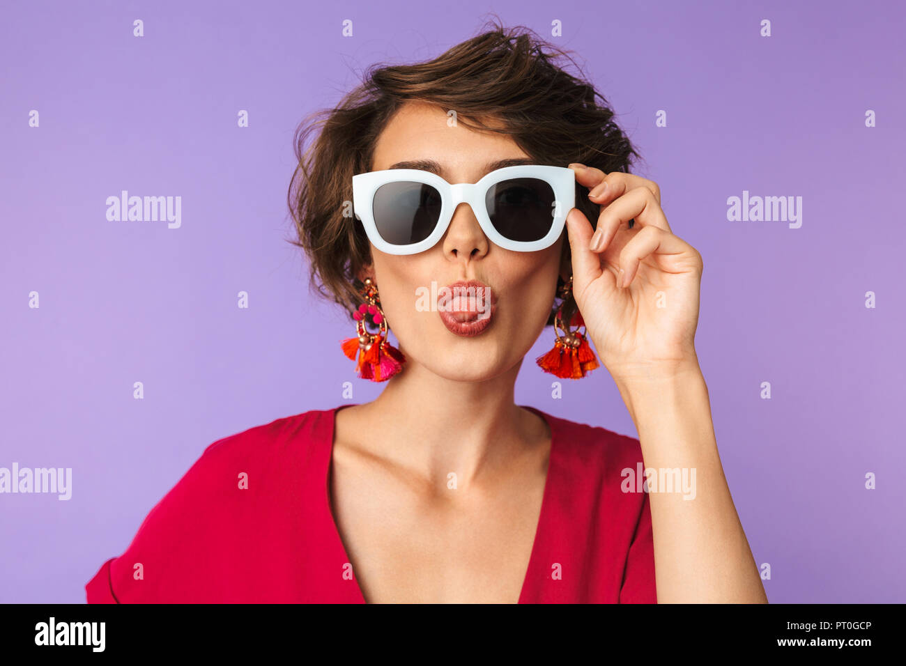 Image de la superbe brune femme 20s en chapeau de paille et lunettes de  sticking tongue out sur fond violet isolés Photo Stock - Alamy
