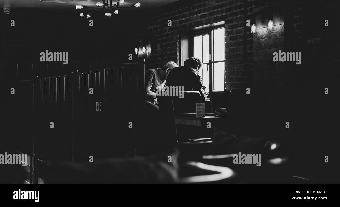 Deux adultes en conversation dans une forte lumière en noir et blanc Banque D'Images