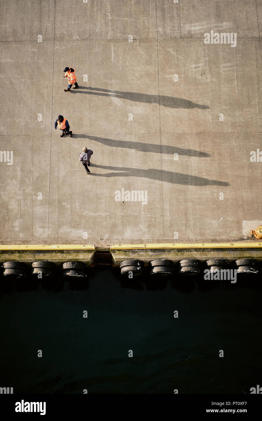 Les quais en attente sur un quai du port de jeter leur ombre dans la faible lumière du soleil - des contrôles aux frontières. Banque D'Images