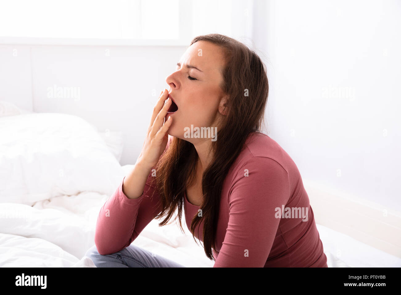 Belle jeune femme le bâillement sur lit dans la chambre Banque D'Images