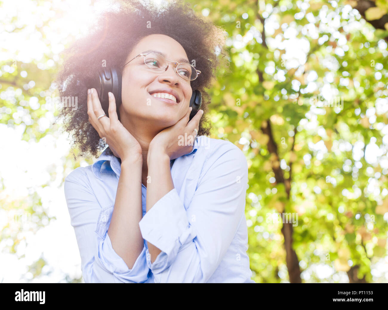 Portrait of Beautiful Happy Young African American Woman Listening Music avec des écouteurs dans la nature, attrayant mixed race female fun outdoor Banque D'Images