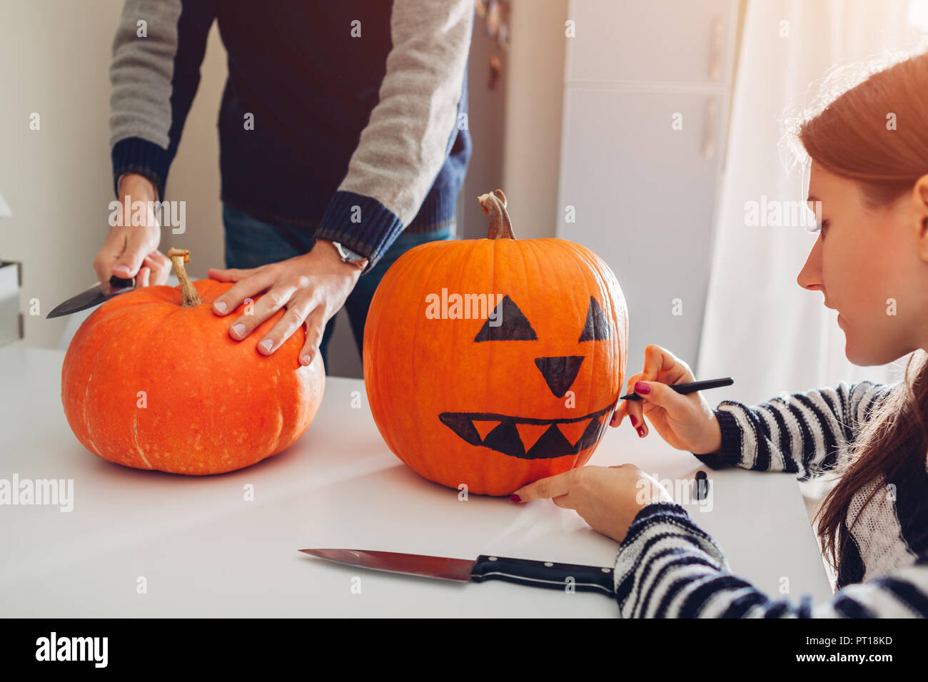 Jeune couple jack-o-lanterne pour halloween sur cuisine. Dessin et découpage de citrouille. Décoration pour maison de vacances Banque D'Images