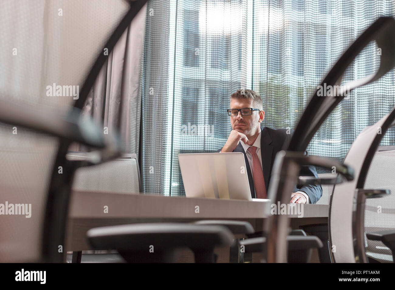 Poland, Warzawa, businessman sitting at conference table dans l''hôtel using laptop Banque D'Images
