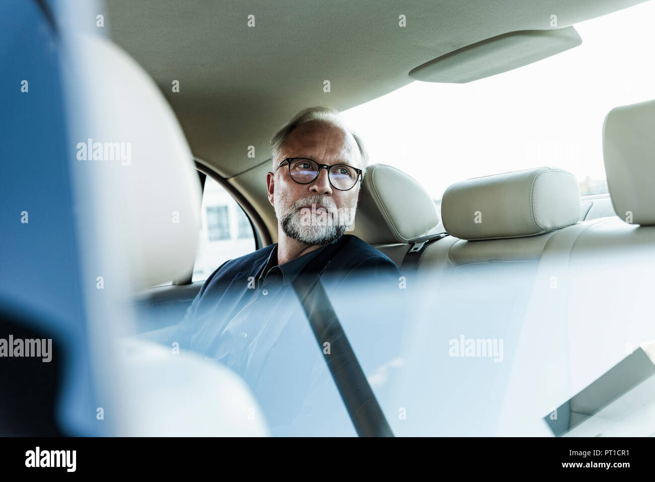 Mature businessman assis sur la banquette arrière en voiture, à la fenêtre de Banque D'Images