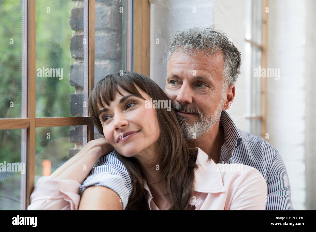 Couple sur appui de fenêtre, regardant par la fenêtre de Banque D'Images