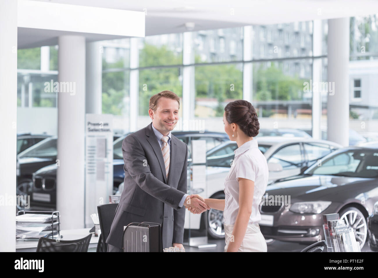 Au concessionnaire, Vendeur et client shaking hands Banque D'Images