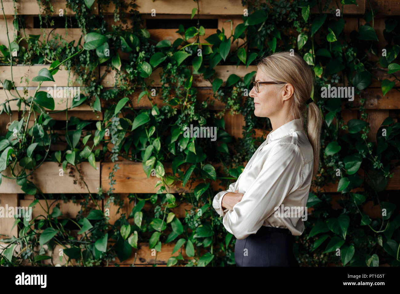 Businesswoman au mur avec plantes grimpantes Banque D'Images