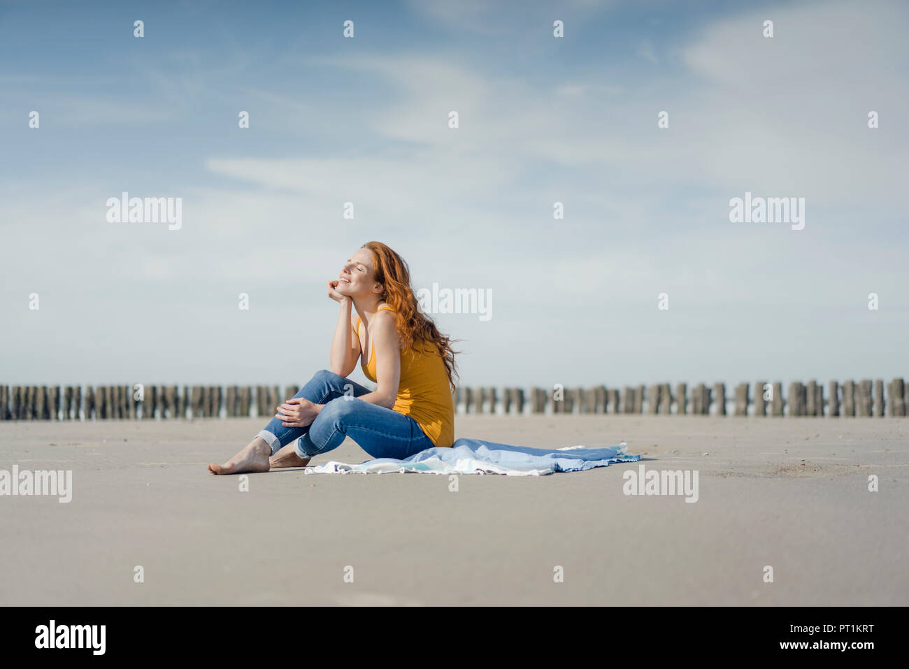 Femme assise sur la plage, profiter du soleil Banque D'Images