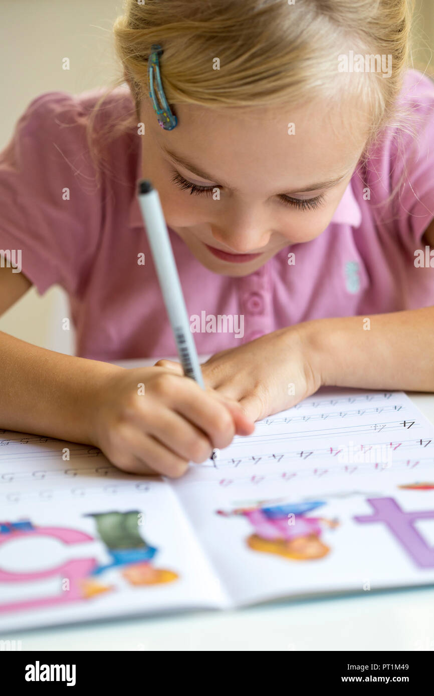 Smiling little girl l'écriture des chiffres dans un livre d'exercices Banque D'Images