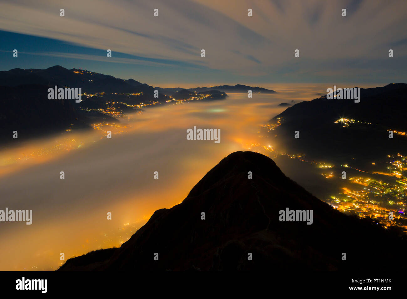 Banc de brume éclairée par les lumières des villes ci-dessous vue depuis le sommet de mont Barro, parc régional du mont Barro, province de Lecco, Lombardie, Italie Banque D'Images