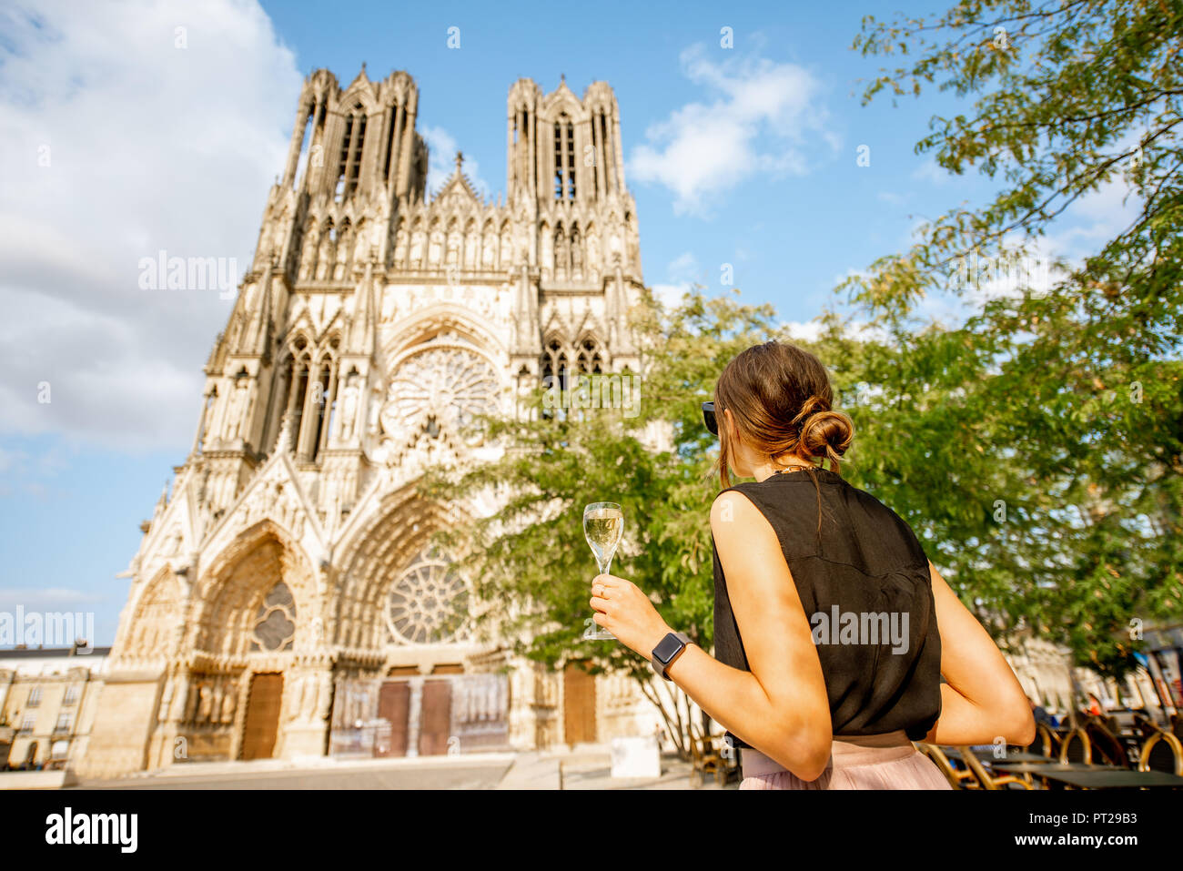 Young woman enjoying champagne debout devant la cathédrale de Reims, ville capitale de la région des vins de Champagne, France Banque D'Images