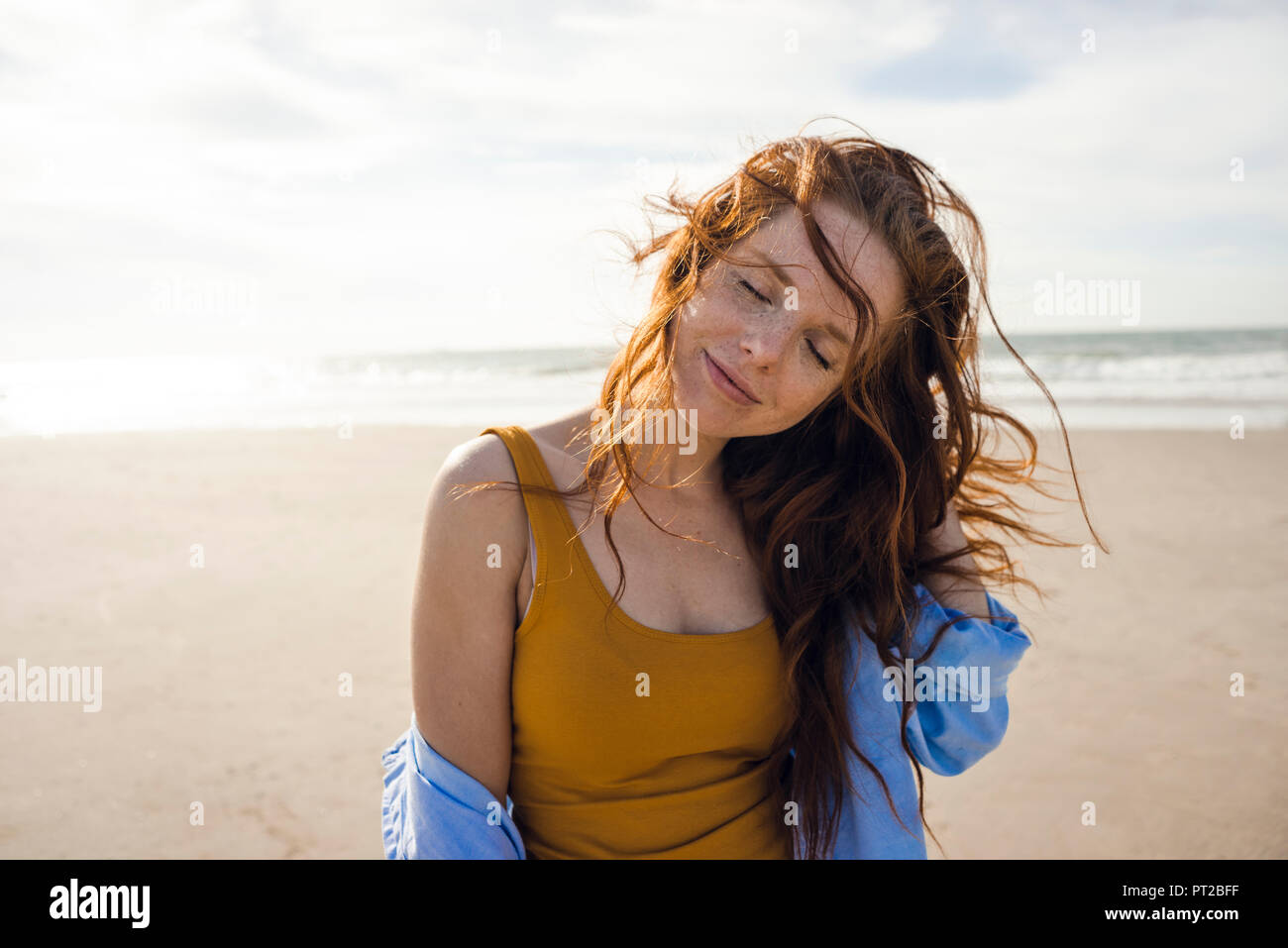 Portrait d'une femme rousse sur la plage, les yeux fermés Banque D'Images