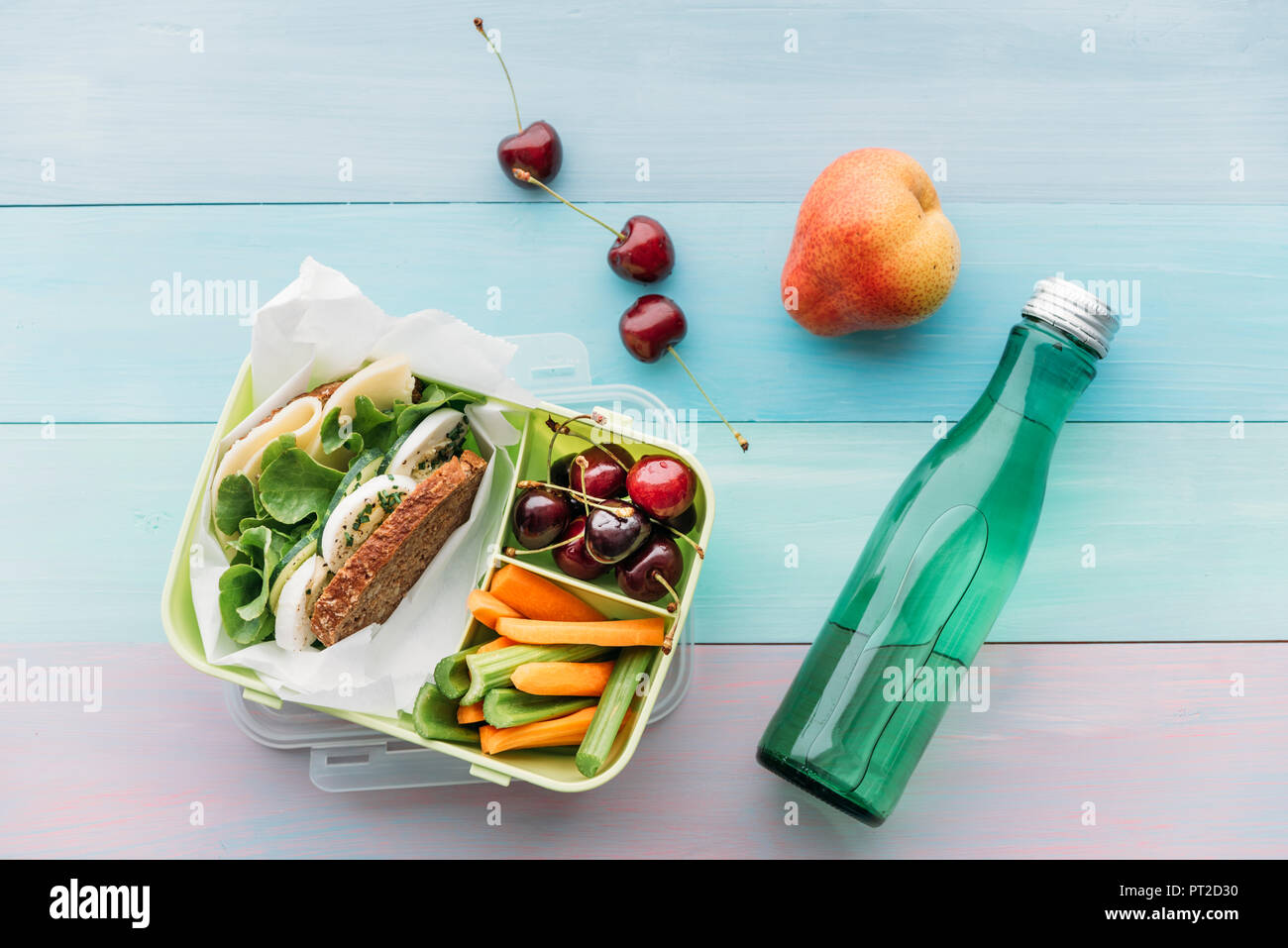 Les aliments sains à l'école dans une boîte à lunch Sandwich végétarien avec du fromage, laitue, concombre, œuf et cresson, tranches de carotte et céleri, cerises et poires Banque D'Images