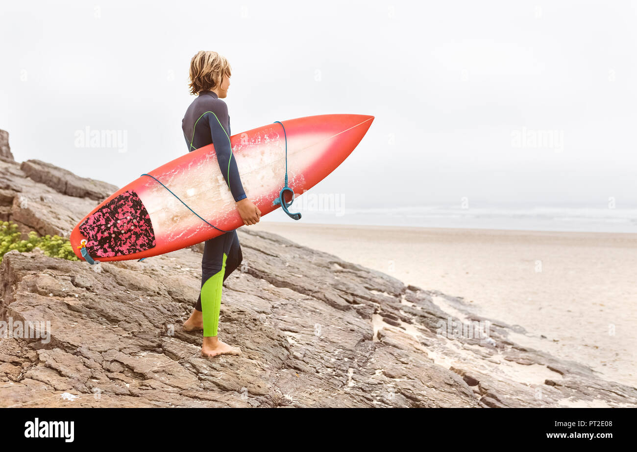 L'Espagne, Aviles, jeune surfer carrying surfboard at la côte Banque D'Images