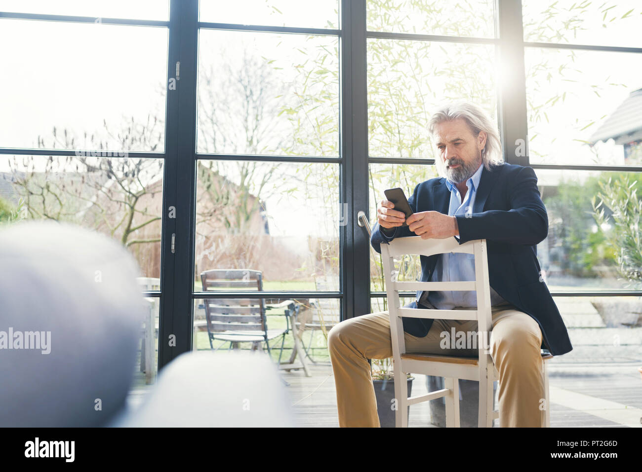 Senior businessman sitting on chair, using smartphone Banque D'Images