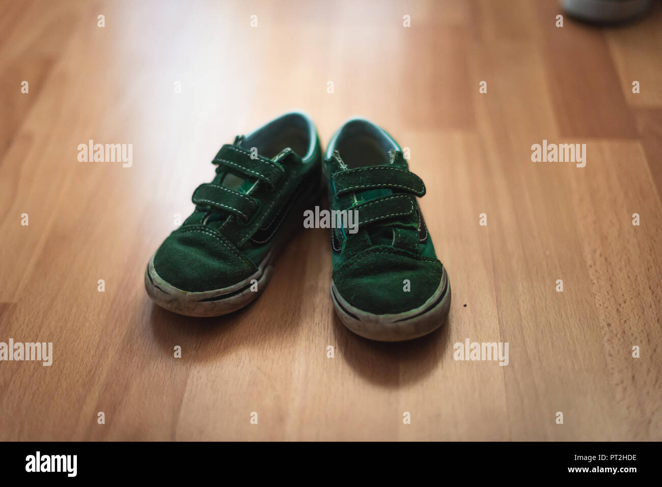 Portés et boueux paire de chaussures d'enfant sur un sol en bois d'une salle de séjour. Banque D'Images