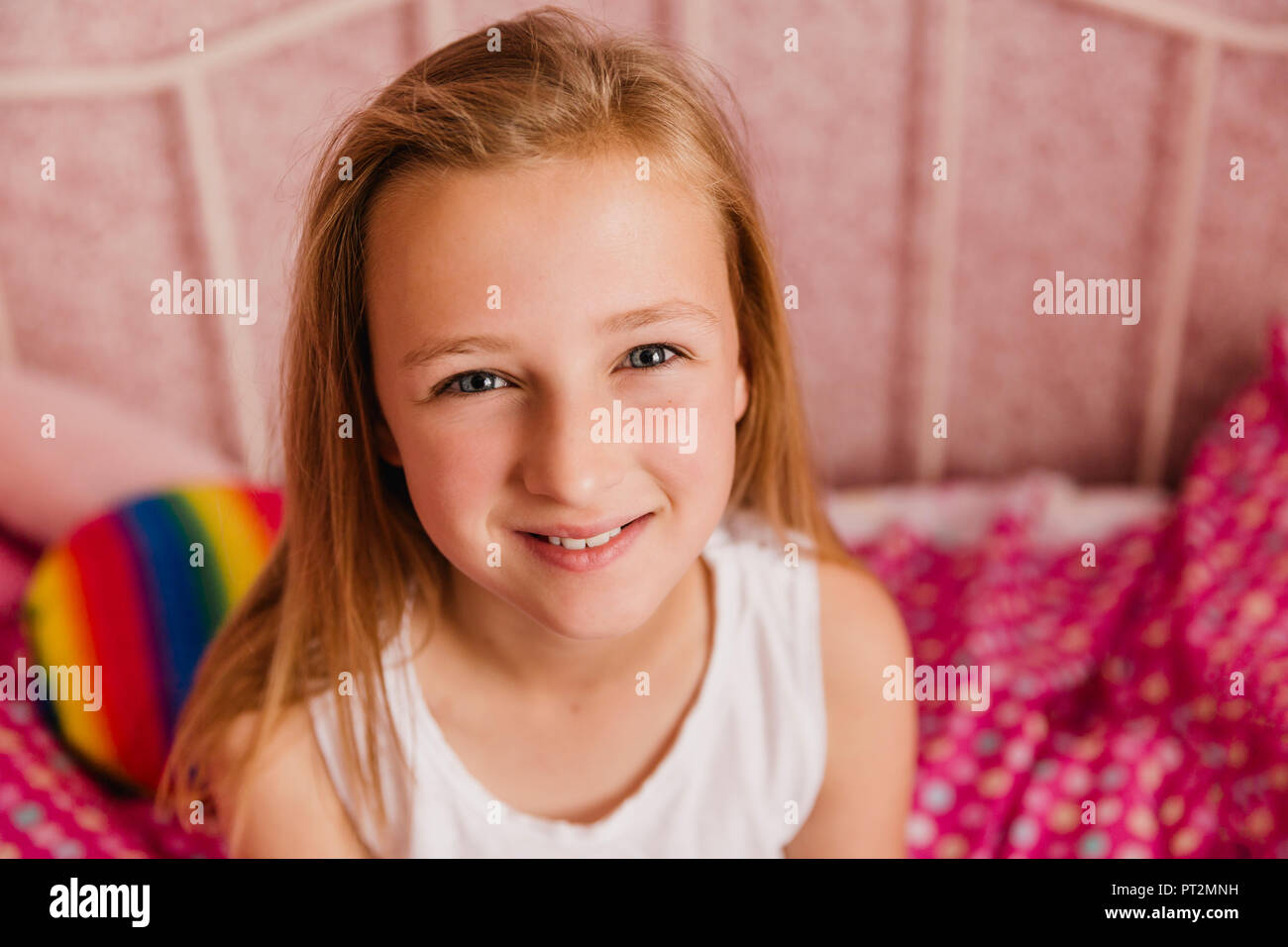 Portrait of smiling little girl in bedroom Banque D'Images