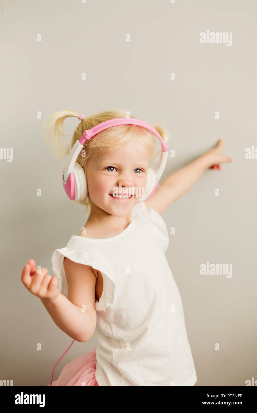 Portrait de petite fille blonde avec des écouteurs dancing Banque D'Images