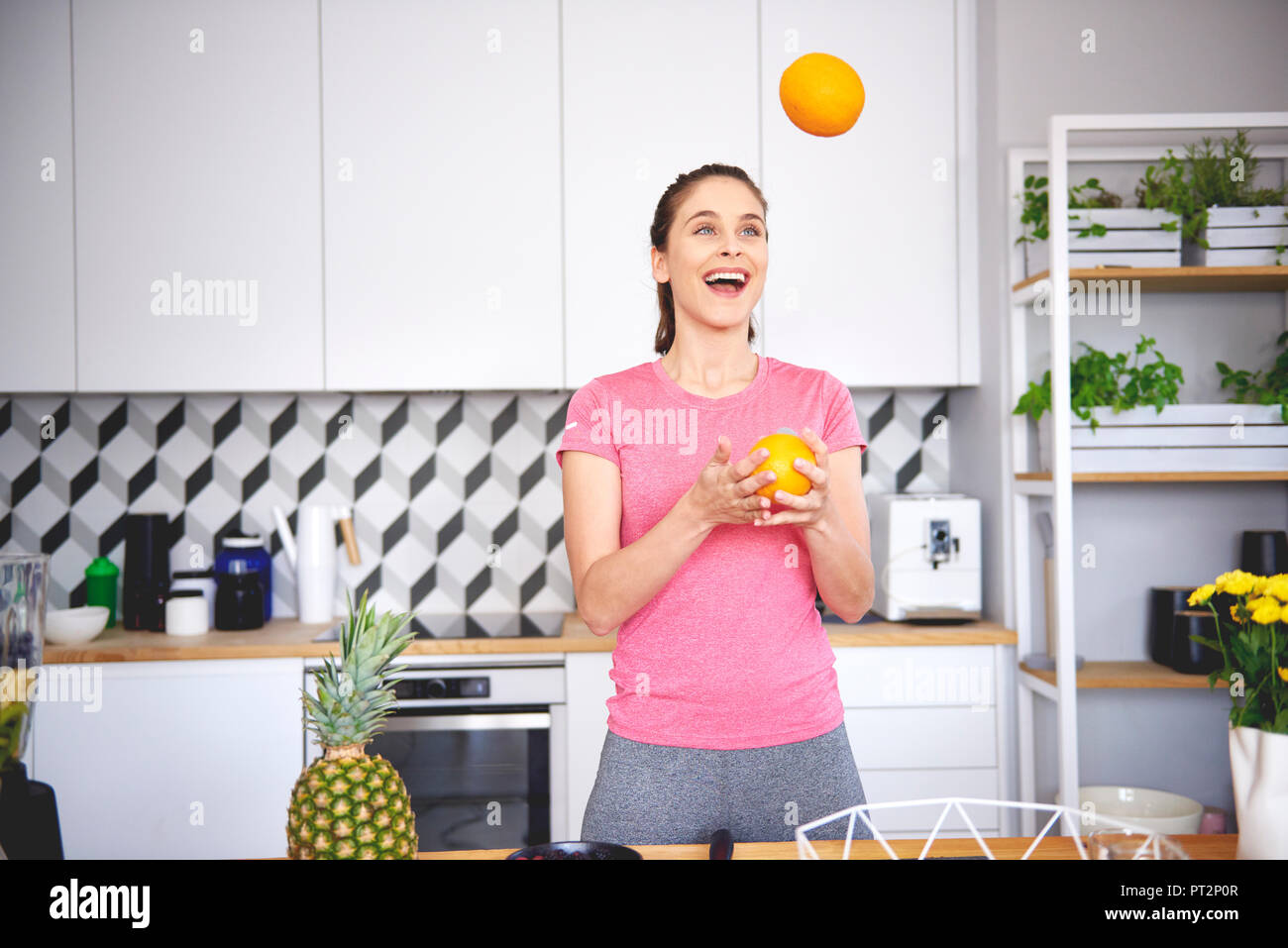 Portrait de jeune femme à jongler avec des oranges dans la cuisine Banque D'Images