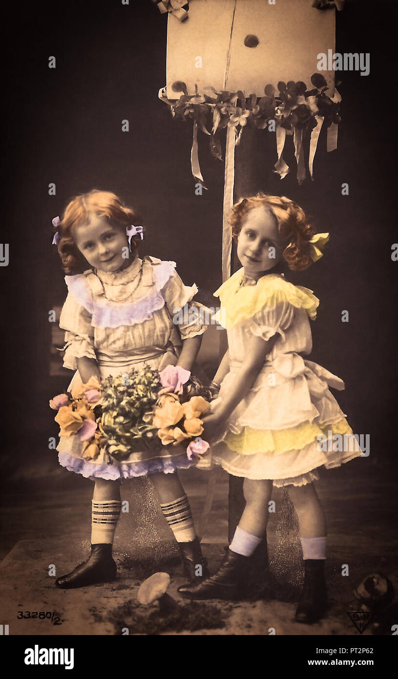 Carte postale vintage de deux petites filles holding Flowers, 1910. Banque D'Images