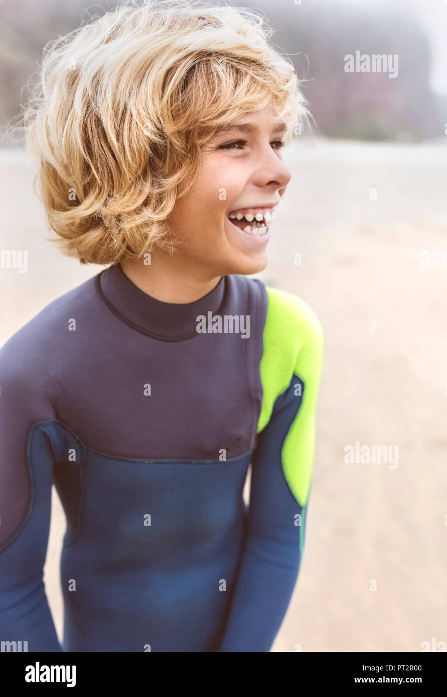 L'Espagne, Aviles, laughing boy en combinaison de plongée sur la plage Banque D'Images