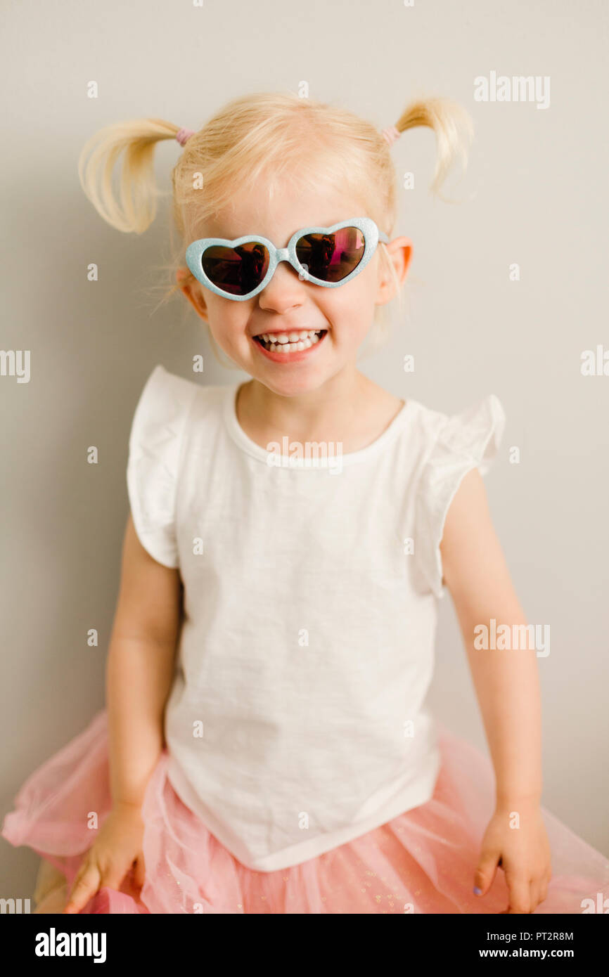 Portrait de petite fille blonde portant des lunettes de soleil en forme de cœur Banque D'Images