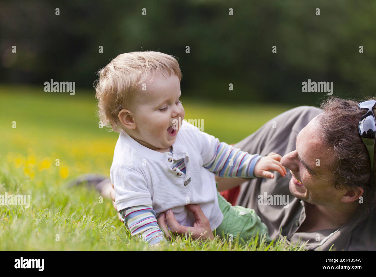 Père et fils couché dans l'herbe s'amusant en été, Bonn, Allemagne, Banque D'Images