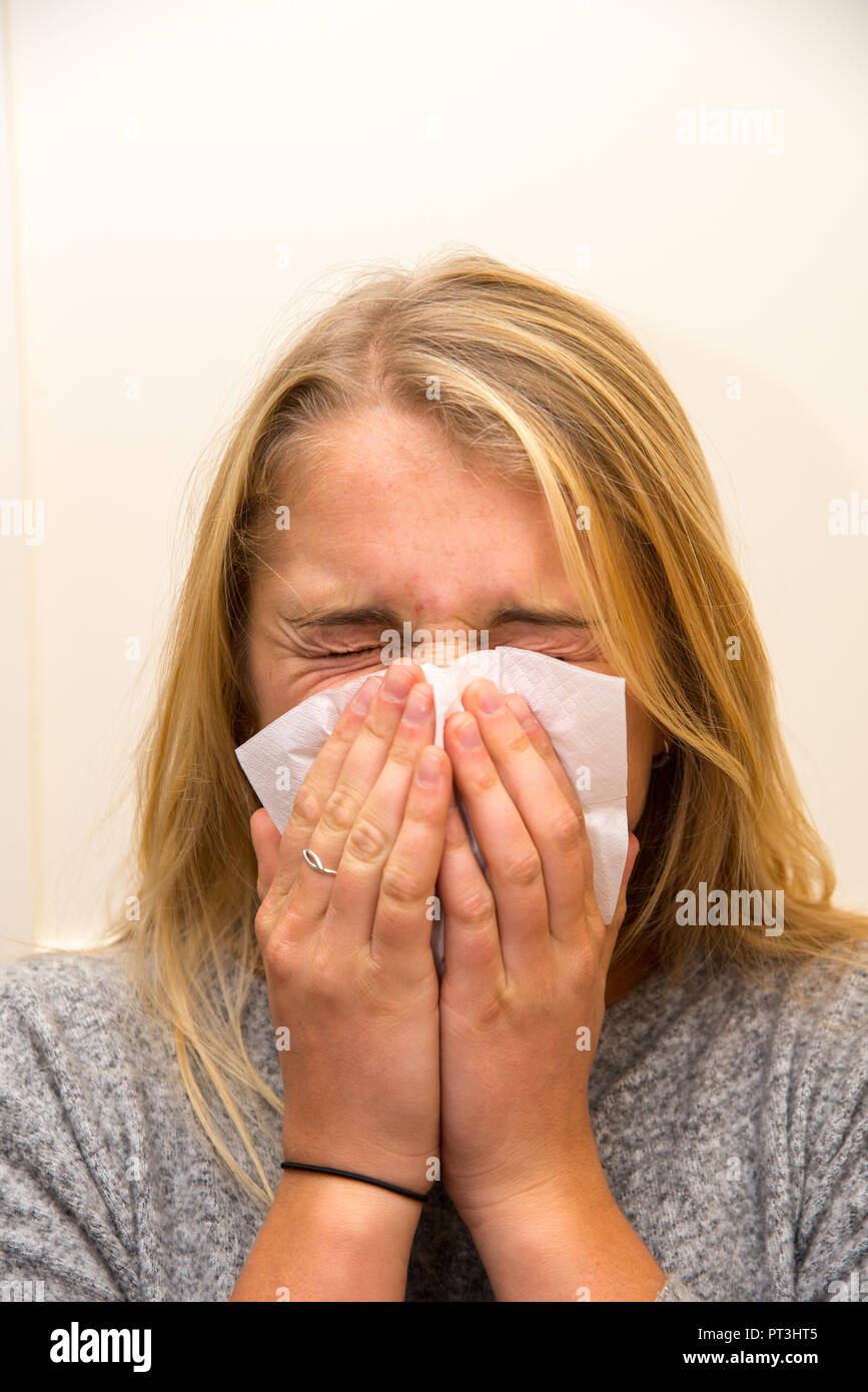 une jeune femme éternuant le nez avec un mouchoir Banque D'Images