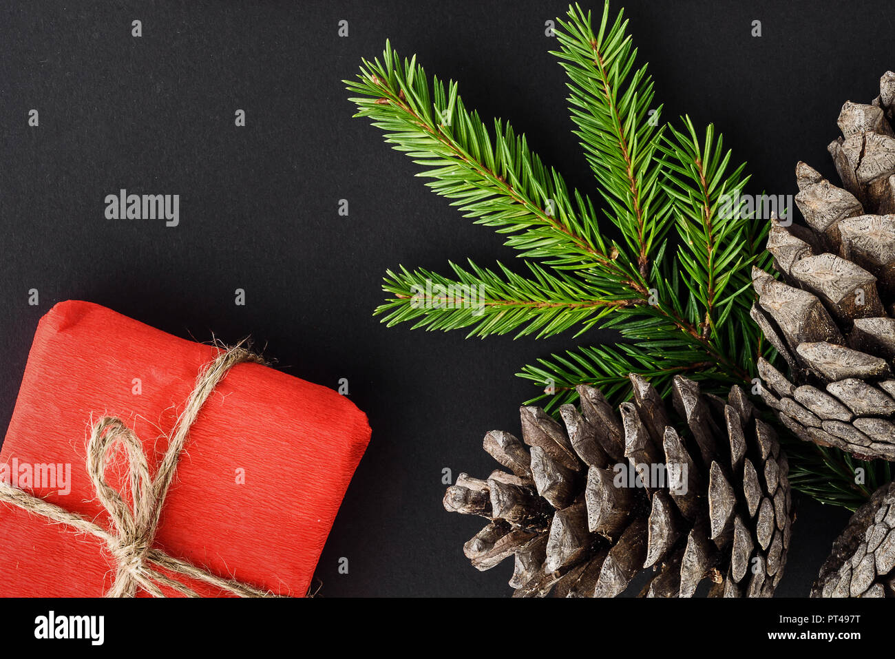 Composition de Noël sur un fond noir. Les cadeaux, les branches de sapin et les cônes. Banque D'Images