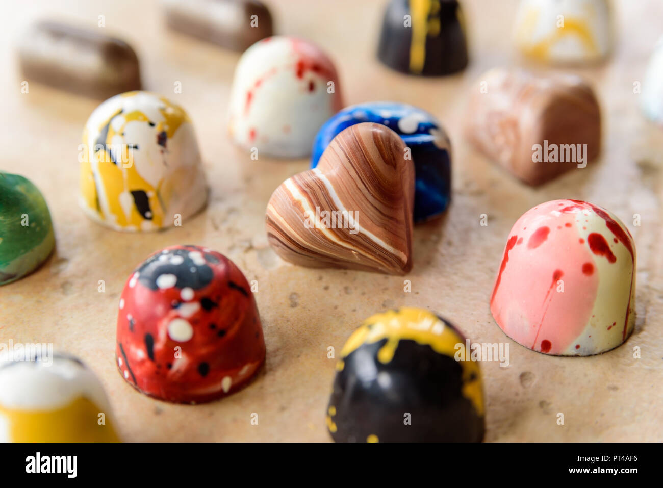 Coeur au chocolat maison s'appuyant sur et entouré par d'autres bonbons colorés. Banque D'Images