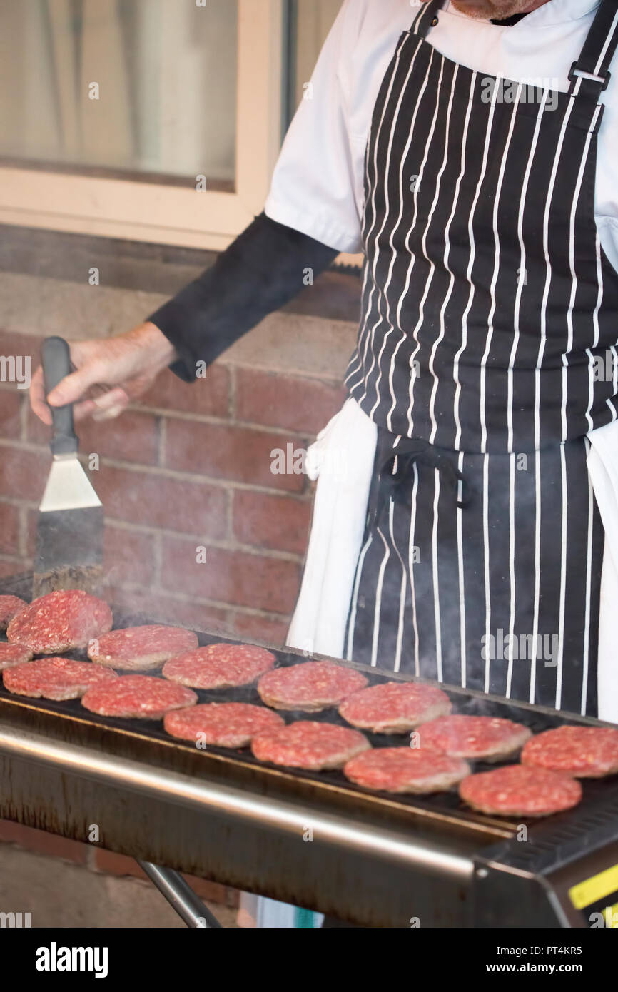 Les galettes sur le barbecue grill de la flamme. Chef cooking hamburgers. Banque D'Images