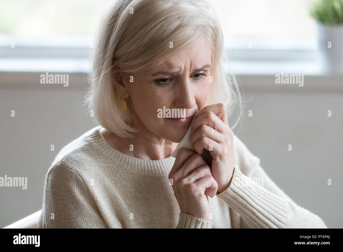 Contrarié femme d'âge moyen d'essuyer les larmes de pleurer se sentir déprimé lonely sans espoir après le divorce, vieille veuve désespérée de la haute pensée de la maladie, la tristesse ou Banque D'Images