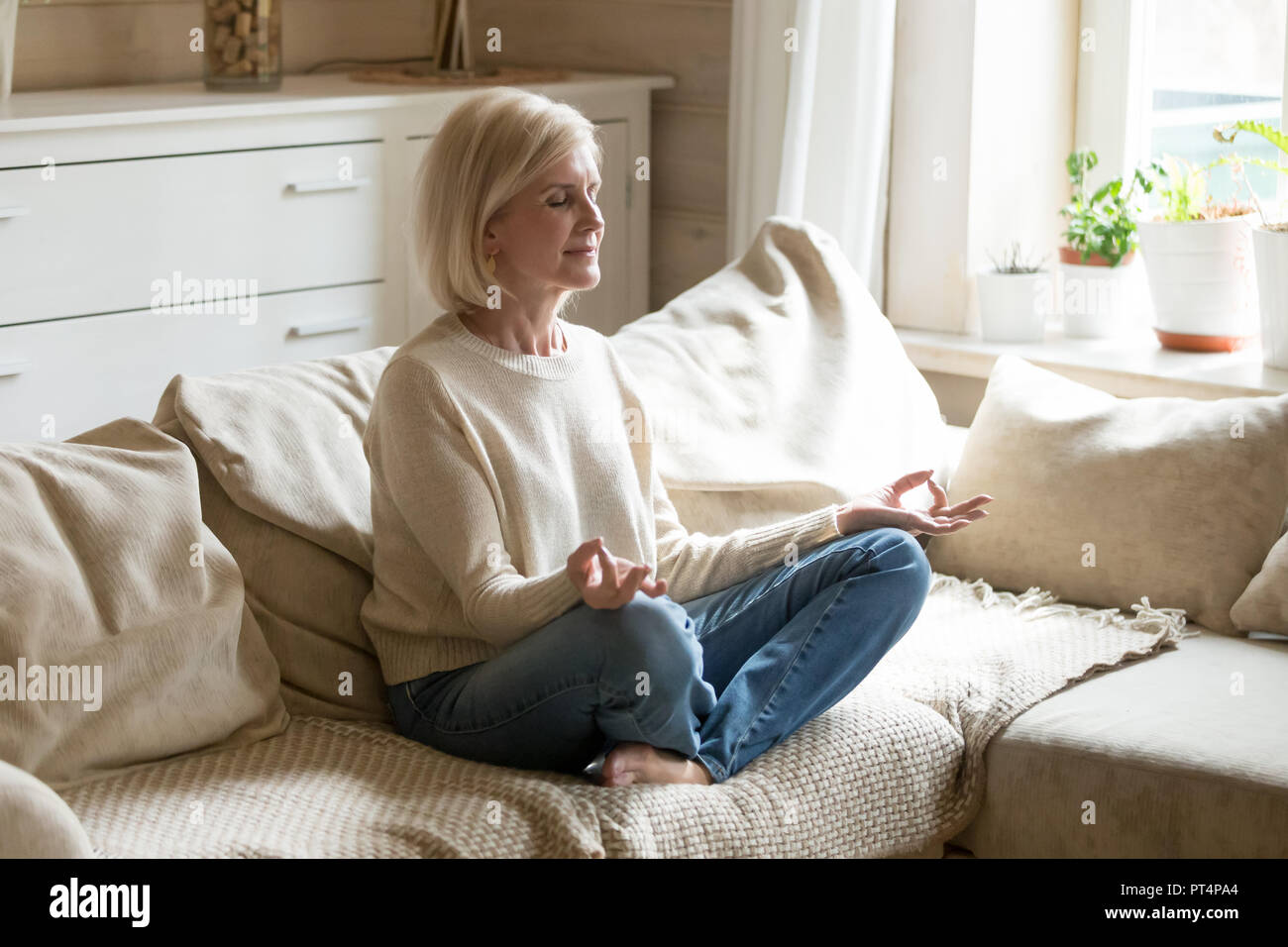 Santé l'esprit mature woman practicing yoga at home Banque D'Images