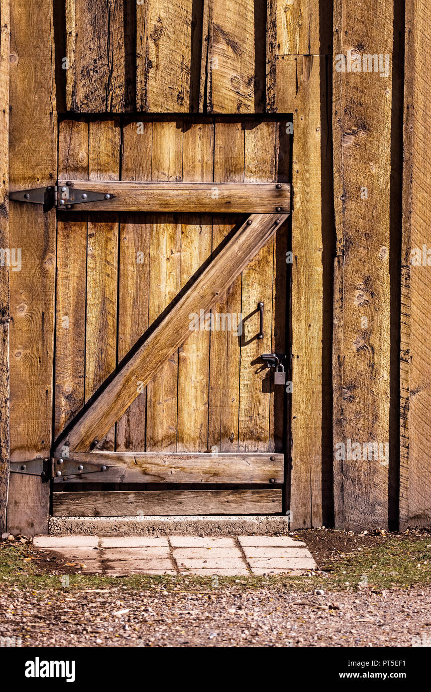 Une lourde porte en bois d'un vieux bâtiment - maison, grange, etc. La porte  est verrouillée de l'extérieur avec un cadenas en métal argent plat sur une  vis métallique. Le b Photo