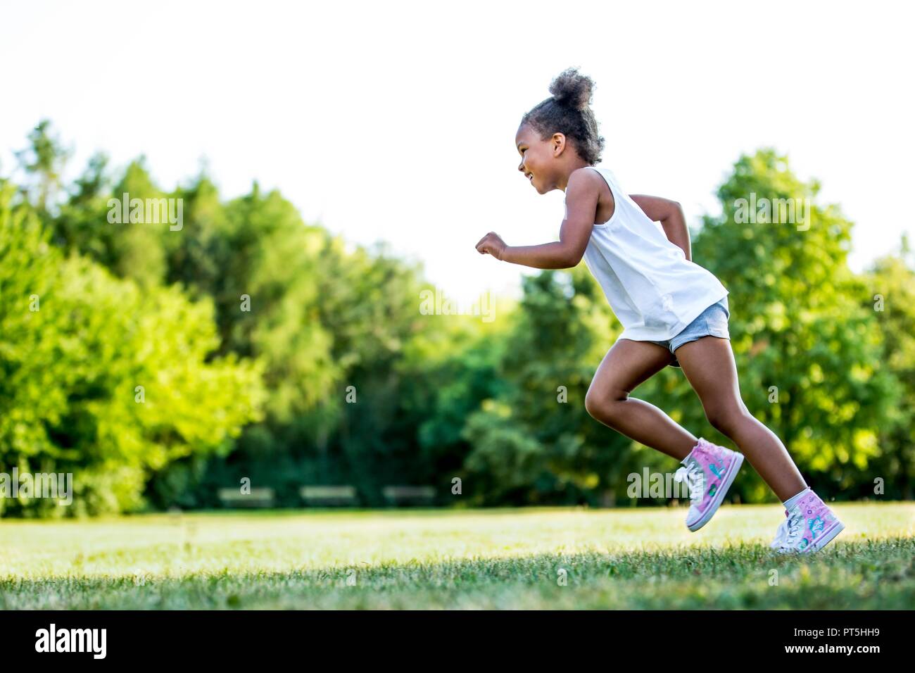 Little girl running in park, souriant. Banque D'Images