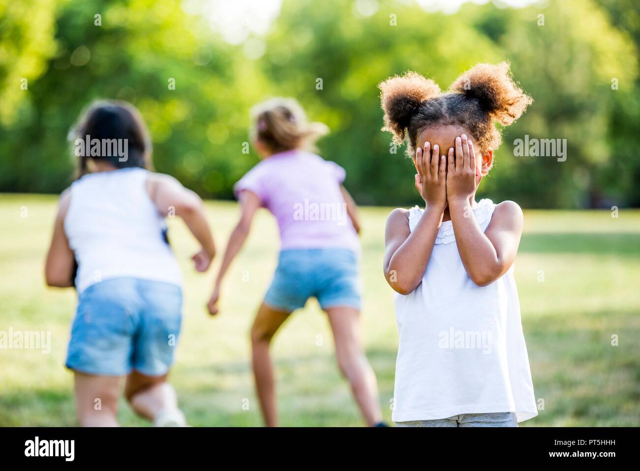De jeunes filles, jouant le jeu mobile en parc. Banque D'Images