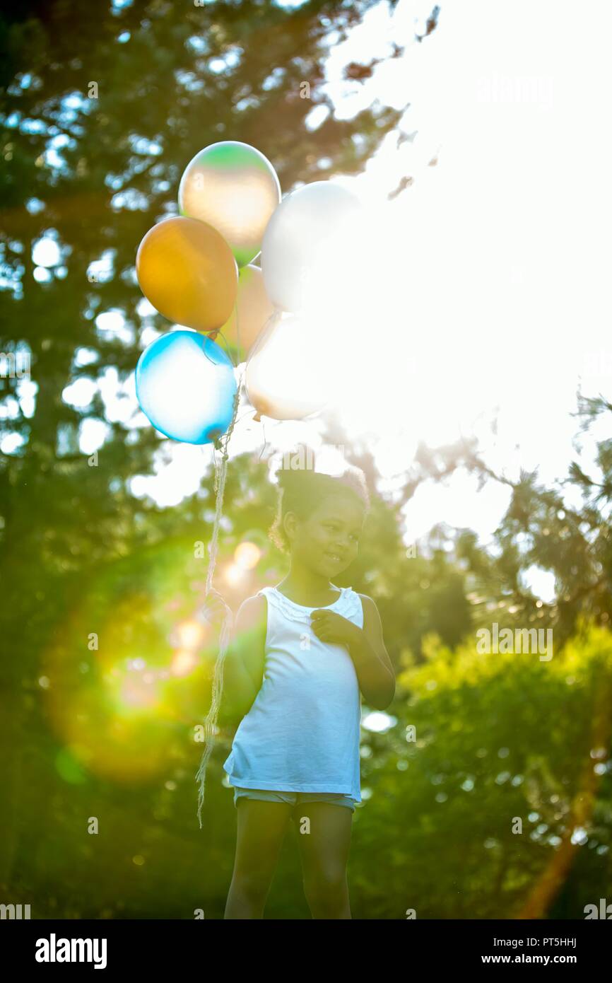 Girl holding bouquet de ballons en parc. Banque D'Images