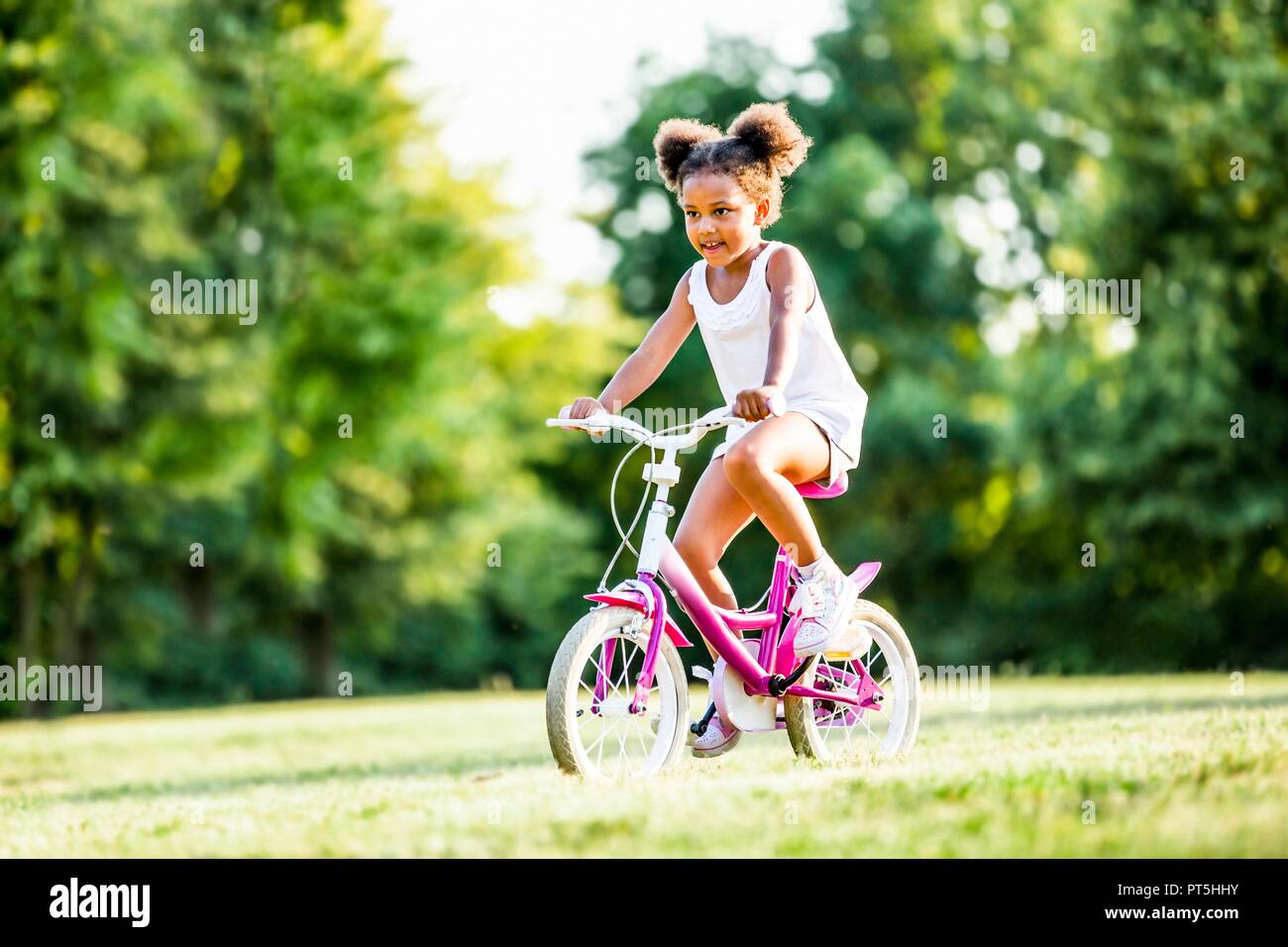 Fille en bottes riding bicycle in park. Banque D'Images