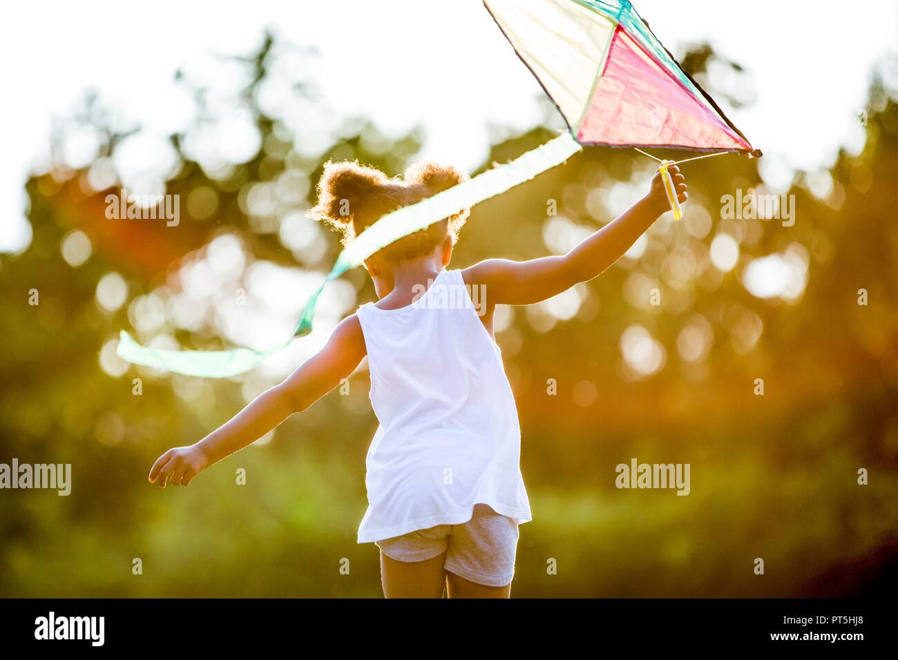 Girl holding kite et fonctionnant en parc. Banque D'Images