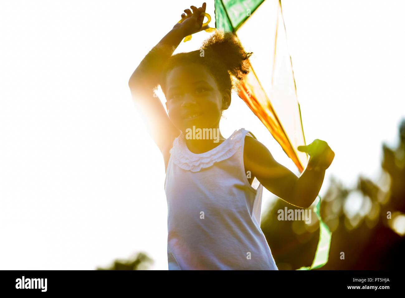 Girl holding kite en park, en souriant. Banque D'Images