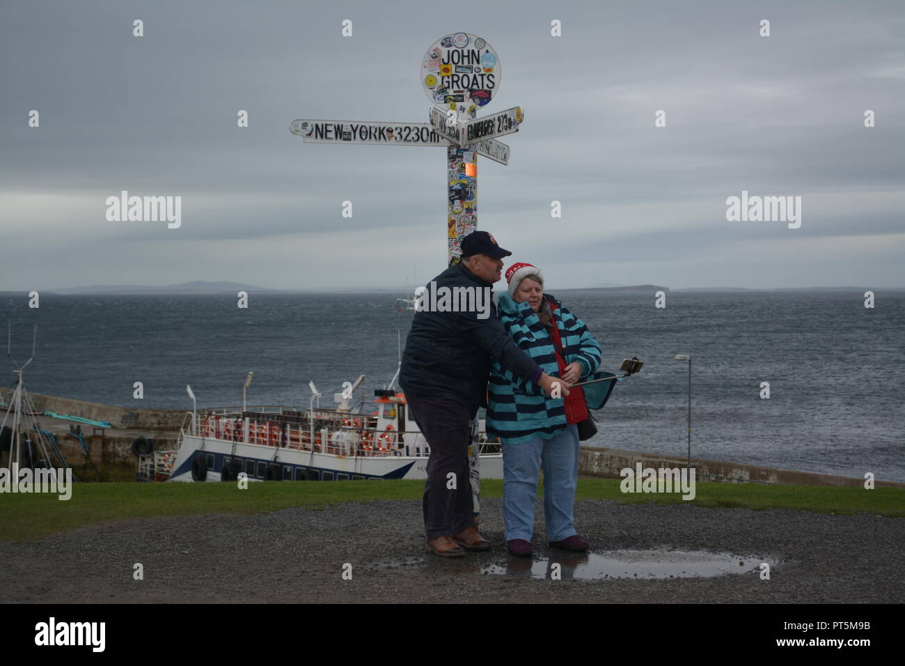 Personnes âgées touristes vacanciers prenant une photographie selfies sous le John O'Groats signpost Caithness Ecosse Grande-Bretagne UK United Kingdom Banque D'Images