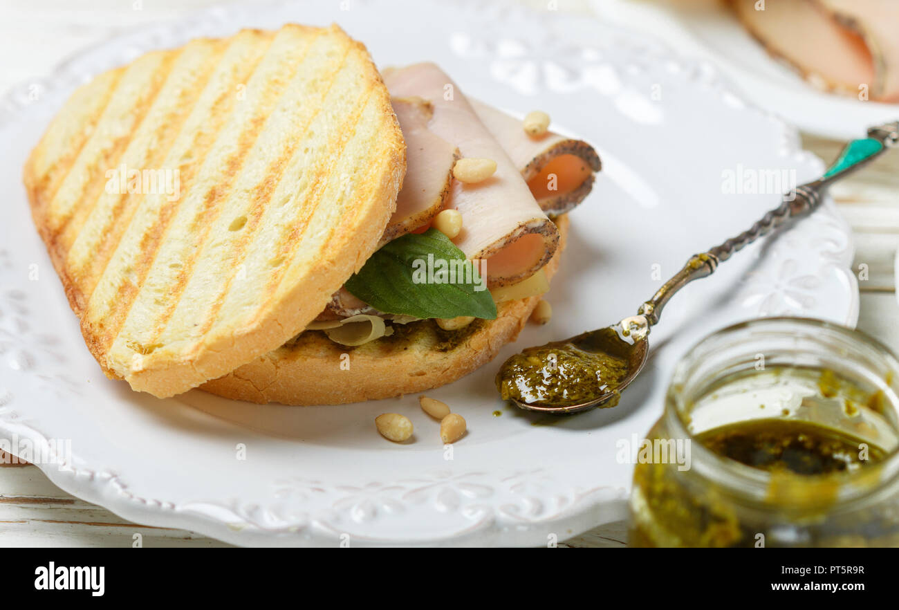Délicieux sandwich avec jambon, fromage cuit au four, sauce pesto et pignons de pin. Collation santé pour les gourmets. Selective focus Banque D'Images